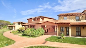A residential complex with multiple houses, a central courtyard, and a clear blue sky. - Studio apartment for 2 people of 27 m2 furnished in Sardinian style.Located on the ground floor with veranda and small garden or first floor with balcony.Composed of living room with kitchenette, 2 joinable single beds, bathroom.Endowed of:- TV- air cond (Vignola Mare / Aglientu)