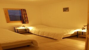 A room with two single beds, a small table, a window with curtains, and a picture on the wall. - Chalet in Huez near Ski Slope (Oz en Oisans)