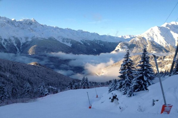 A snowy mountain landscape with a clear sky and a view of a valley below.