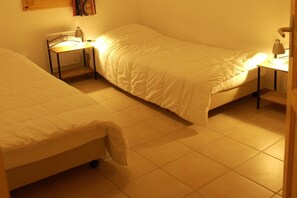 Ein Zimmer mit zwei Betten, jeweils mit Nachttisch und Lampe.