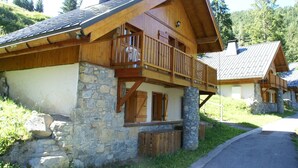 A wooden chalet with stone foundation, wooden balcony, and a stone chimney. - Chalet in Huez near Ski Slope (Oz en Oisans)