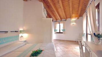 A bedroom with a wooden ceiling, a bed with a decorative headboard, a bedside table, and a window with curtains.