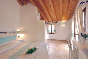 Un dormitorio con techo de madera, una cama con cabecera decorativa, una mesita de noche y una ventana con cortinas.