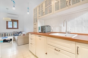 A kitchen with a wooden countertop, a built-in oven, a sink, and a window with blinds.