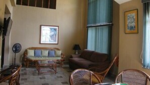 A living room with a sofa, chairs, a fan, and a ceiling fan.