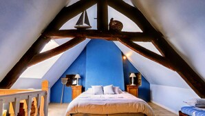 Un dormitorio con techo inclinado, una cama, dos mesitas de noche y una baranda de madera.