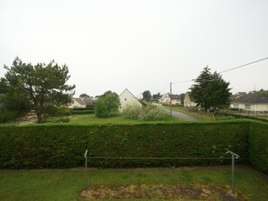Houses line a quiet road, surrounded by a well-maintained hedge.