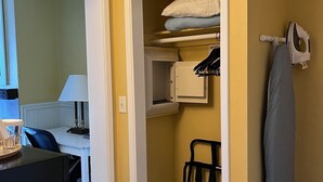 Une petite pièce comprenant un lit, un petit placard et un bureau avec une lampe.