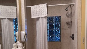 Une salle de bain équipée d’un lavabo, d’un miroir, d’une douche et d’un porte-serviettes.