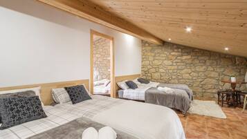 Ein Schlafzimmer mit zwei Betten, Steinwänden, Holzbalkendecke und einem Steinkamin.
