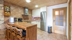 Una cocina con barra de madera, pared de piedra, electrodomésticos de acero inoxidable y suelo de baldosas.