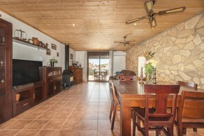 A spacious kitchen with a stone wall, wooden ceiling, and a large TV. - Holiday Home 'El Petit Maialenc' with Mountain View and Air Conditioning (Maials)