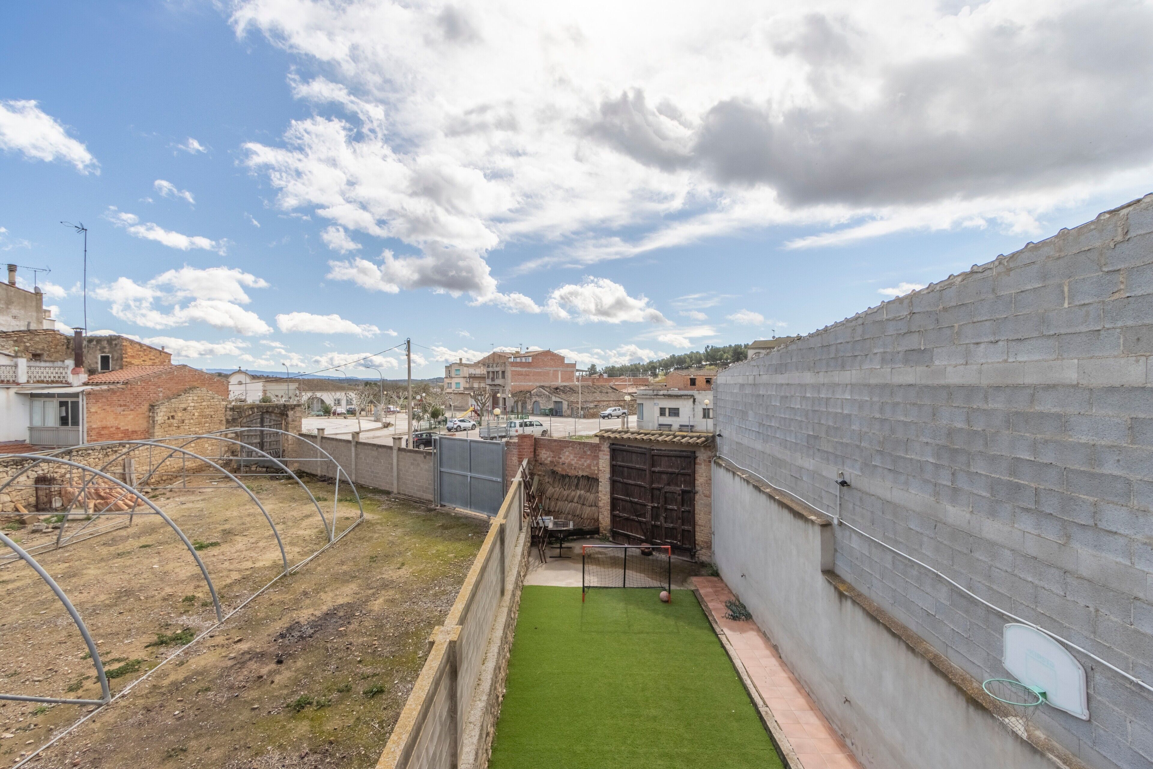 Une cour avec une pelouse verdoyante, un mur de briques et une clôture en métal.