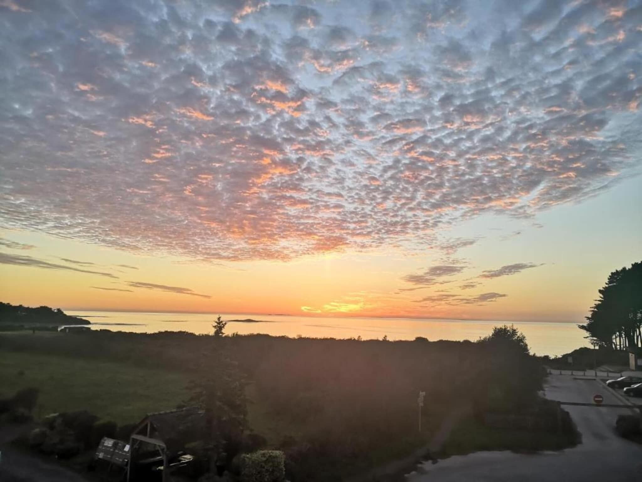 Een zonsondergang boven een wateroppervlak met een bewolkte lucht.