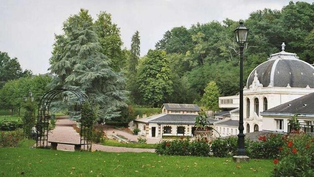Un giardino con un gazebo, un vialetto e un edificio con una cupola.