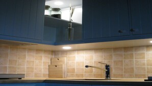 A kitchen with blue cabinets, a wooden cutting board, and a sink with a faucet. - Holiday Home in Ceaucé near Mont Saint Michel (Céaucé)