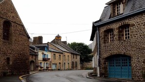 A narrow street with stone buildings, a blue door, and a lamp post. - Holiday Home in Ceaucé near Mont Saint Michel (Céaucé)