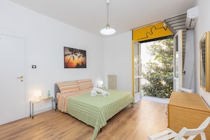 A bedroom with a bed, bedside table, lamp, and a painting.