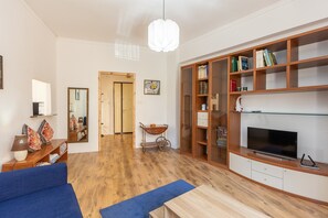 A living room with a sofa, television, bookshelf, and a mirror.