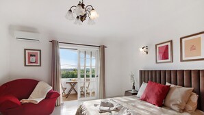 A bedroom with a bed, a red chair, a balcony, and a view of the outdoors. - Villa 'Casa Judite' with Private Terrace, Balcony and Wi-Fi (Lagoa)