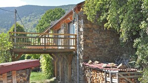 A rustic stone building with a wooden balcony, surrounded by greenery and mountains. - Villa in Ayguatébia-Talau with Garden & BBQ (Ayguatebia-Talau)