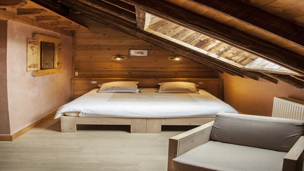 A cozy attic bedroom with a wooden sloped ceiling, a single bed with pillows, a wooden chair, and a small window. - Mansion in Albertville near Ski Slopes (Mercury)