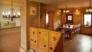 A wooden cabin interior with a dining area, wooden cabinets with heart cutouts, a chandelier, and framed pictures on the walls. - Mansion in Albertville near Ski Slopes (Mercury)