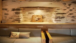 A rustic room with stone walls, a wooden bench, and a cushioned bench with a heart-shaped pillow. - Mansion in Albertville near Ski Slopes (Mercury)