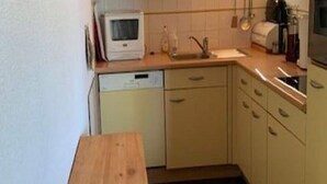A small kitchen with a wooden table, a white microwave, a sink, and light-colored cabinets. - Chalet in Vallandry near Paradiski Ski Area (Vallandry)