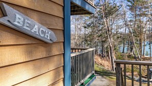 A wooden building with a 'BEACH' sign, a wooden deck, and a view of trees and water. - Private Coveside Escape. Minutes to Acadia (Trenton)
