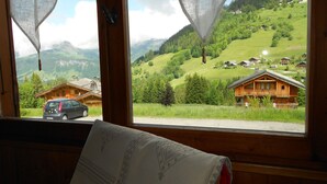 A room with a large window overlooking a green valley with houses and a car parked outside. - Chalet in Notre-Dame near Ski Lift (Notre Dame de Bellecombe)