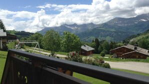 A scenic view from a balcony overlooking a mountain landscape with wooden buildings and a clear sky. - Chalet in Notre-Dame near Ski Lift (Notre Dame de Bellecombe)