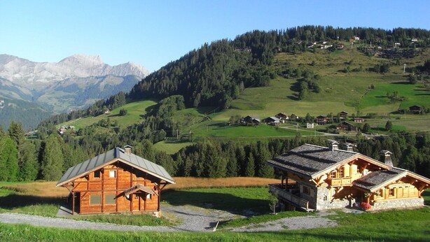 A wooden cabin with a sloped roof and a small porch, surrounded by a lush green landscape and mountains in the background. - Chalet in Notre-Dame near Ski Lift (Notre Dame de Bellecombe)