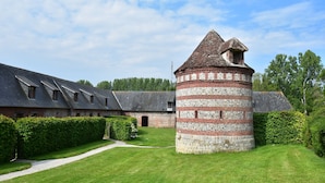 Ein historisches Gebäude mit einem zentralen Turm und einem langgestreckten, schräg-gedachten Bau.