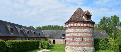 A historic building with a central tower and a long, sloped-roofed structure.