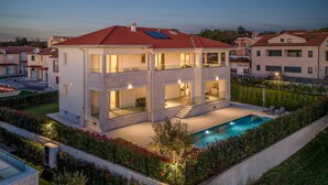 Une maison moderne à deux étages, dotée d’une piscine, de grandes fenêtres et d’un jardin bien entretenu.