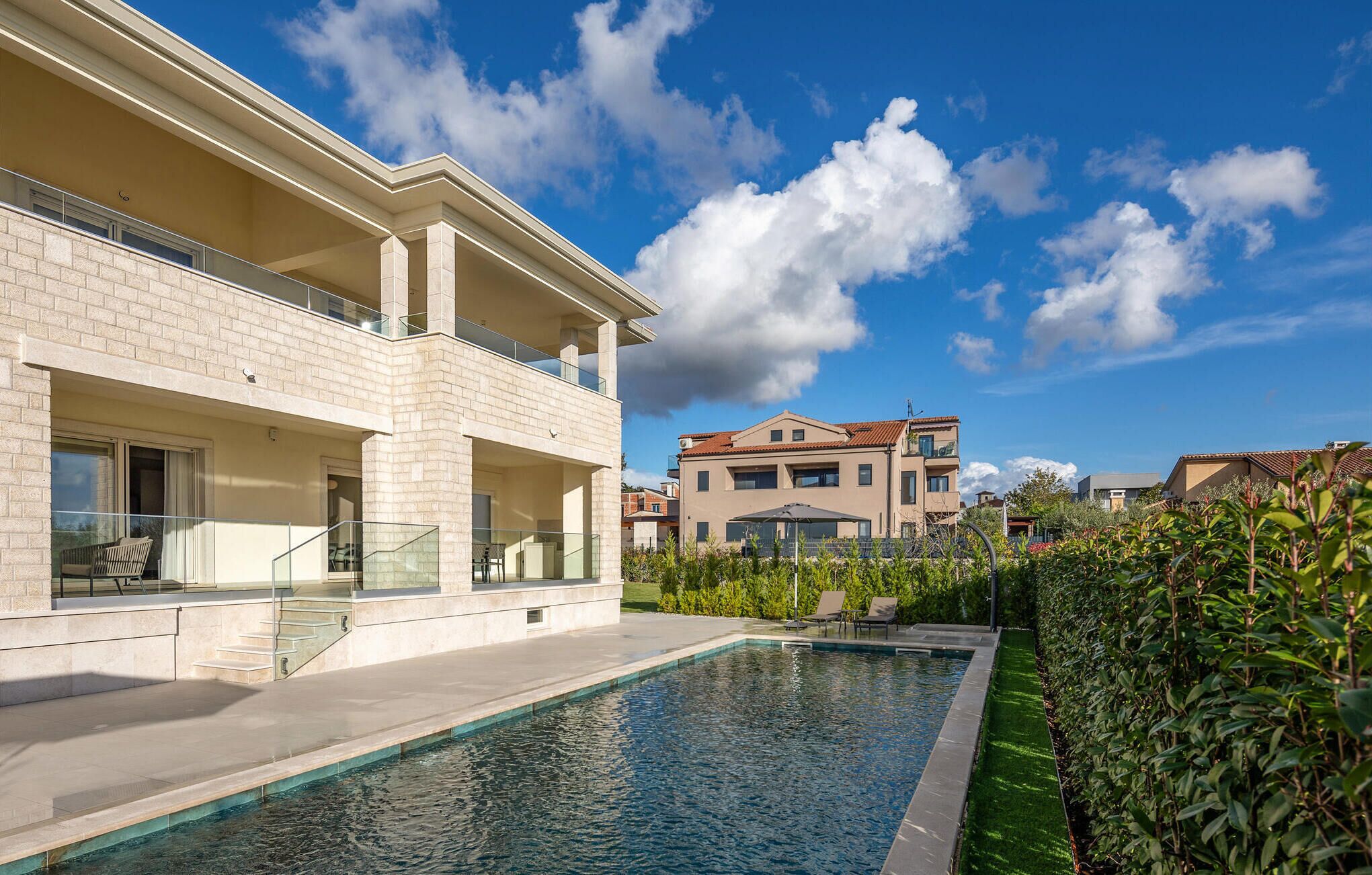 Uma casa moderna de dois andares com piscina, varanda e jardim.