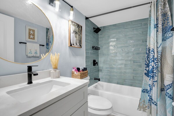 Un baño moderno con un lavamanos blanco, grifo negro y ducha con pared de azulejos azules.