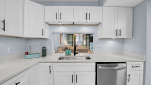 A modern kitchen with white cabinets, a stainless steel sink, and a dishwasher.