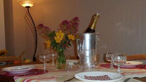 Ein Esstisch, gedeckt mit Tellern, Besteck und einer Champagnerflasche in einem silbernen Kübel.