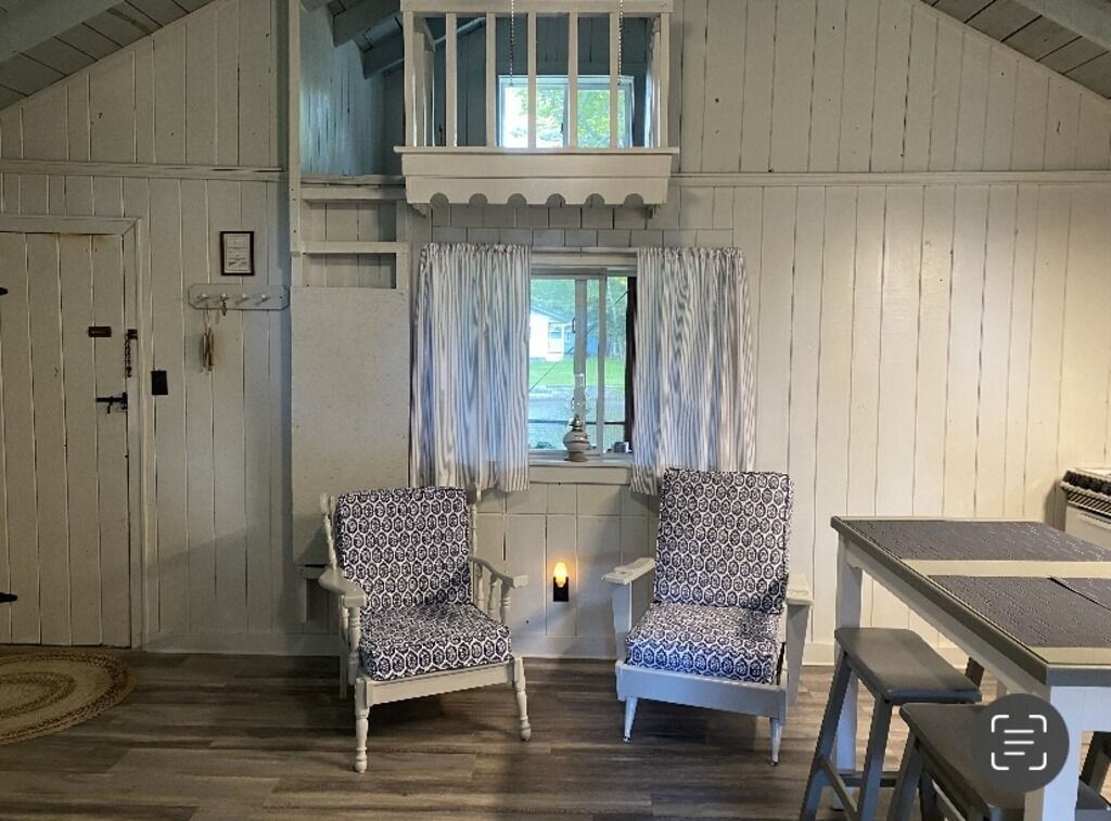 A cozy room with two patterned chairs, a small table, and a window with curtains.