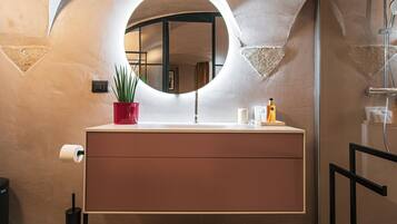 Une salle de bain avec un miroir rond, un lavabo et une plante en pot.