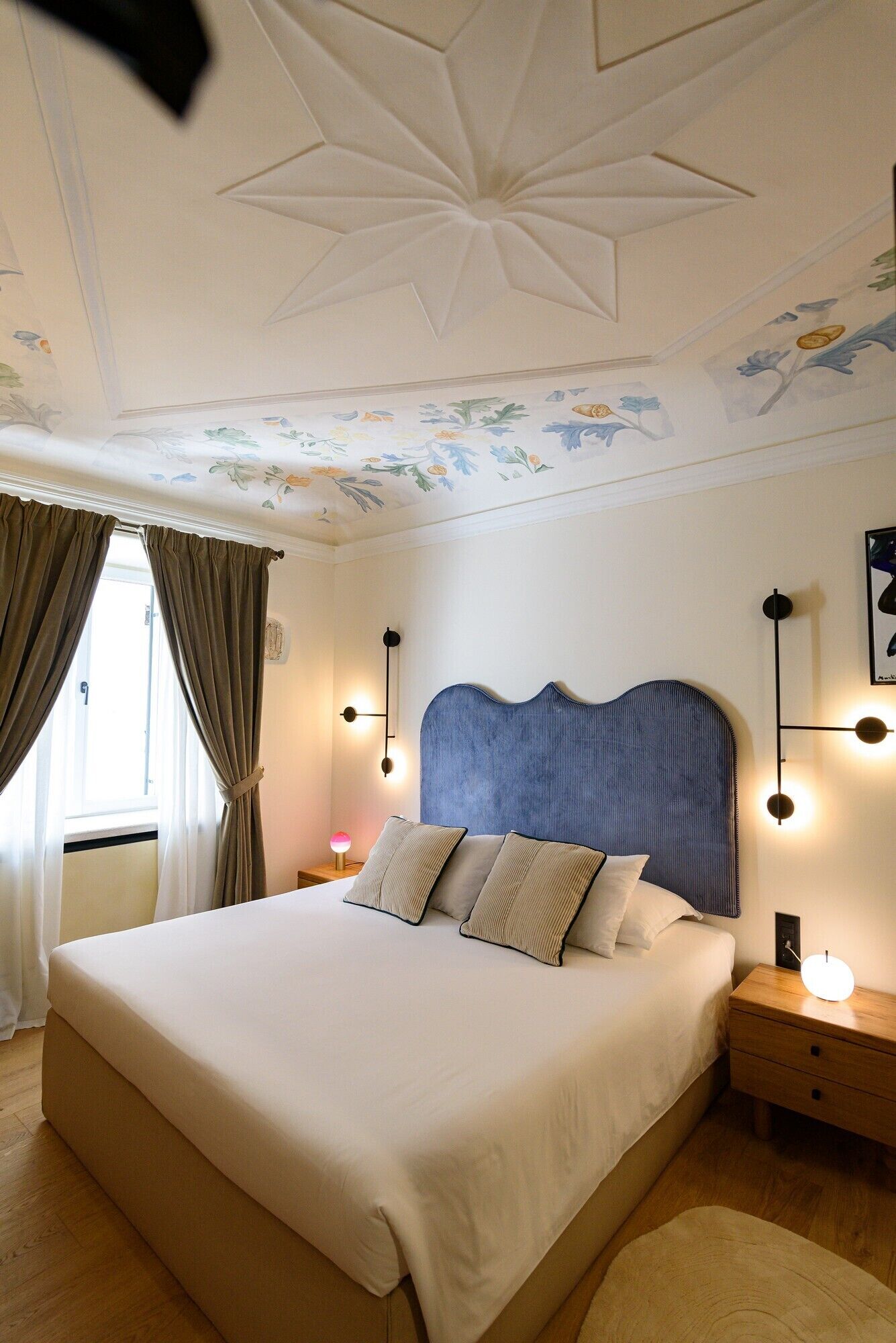 Un dormitorio con una cama grande, un techo decorativo y una mesita de noche con lámpara.