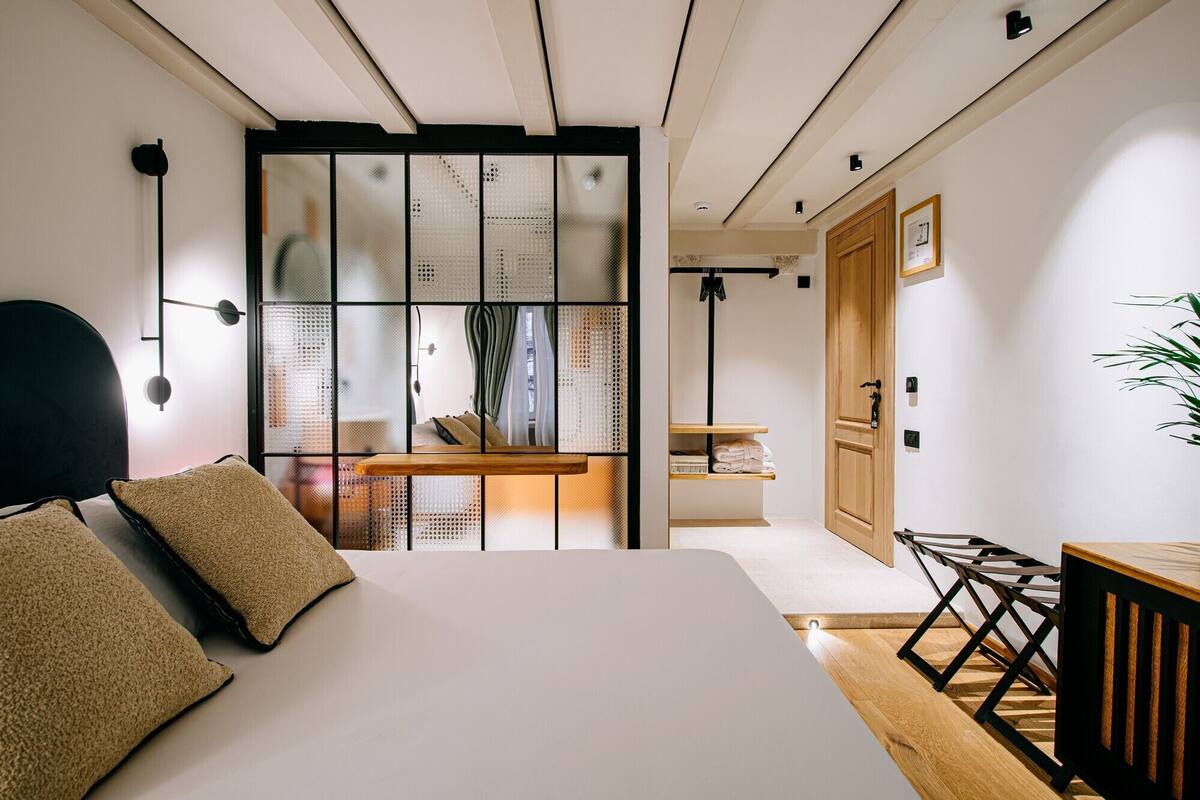 Un dormitorio moderno con una cama grande, un banco de madera y una puerta corrediza con diseño tejido.