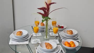 A breakfast table with croissants, oranges, and orange juice.