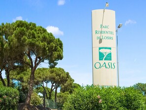 Een hoog, beige bord met groene tekst en een boomlogo, dat een woongebied OASIS aangeeft.