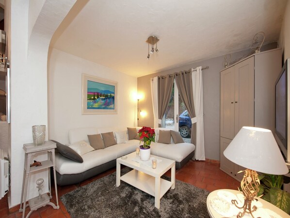Un salon avec un canapé, une table basse sur laquelle se trouve un vase, une lampe et un tableau accroché au mur.