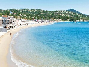 A beach with clear blue water, a sandy shore, and buildings in the background. - Holiday Home in Fréjus near Sea and Lake (Fréjus)