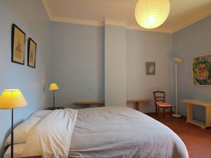 A bedroom with a bed, bedside tables, a chair, and a desk. There are two lamps, a hanging light fixture, and artwork on the walls. - Holiday Home in Provence with Private Pool (Cavaillon)