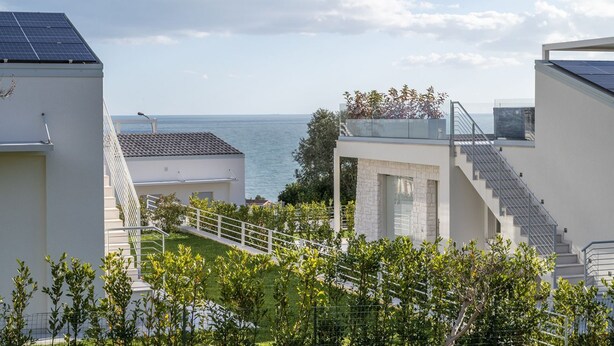 Un edificio moderno con vista al mar, una escalera y paneles solares.